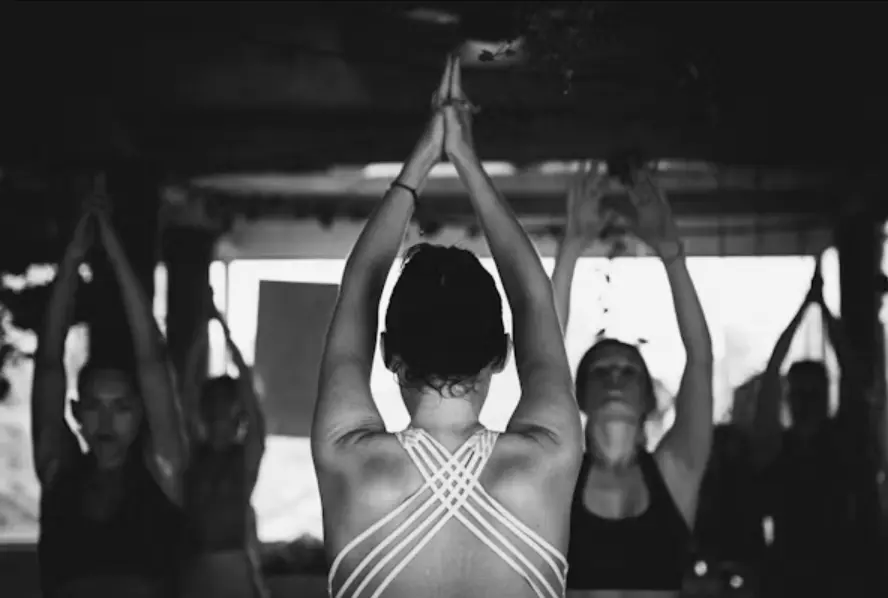 Yoga class with students raising hands in prayer position